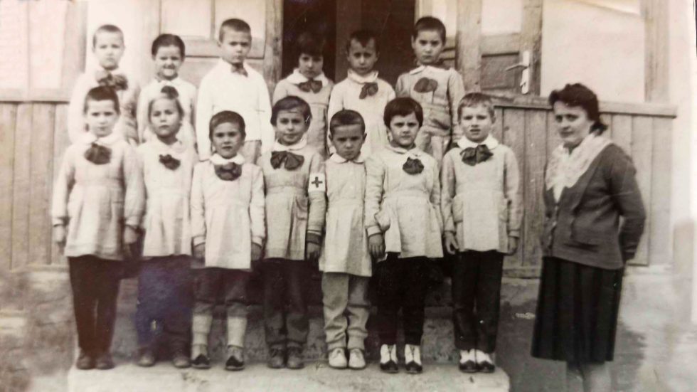 Bambini dell’asilo in posa per una foto d’infanzia negli anni ’60, simbolo di semplicità e affetto familiare tra neve e giochi.