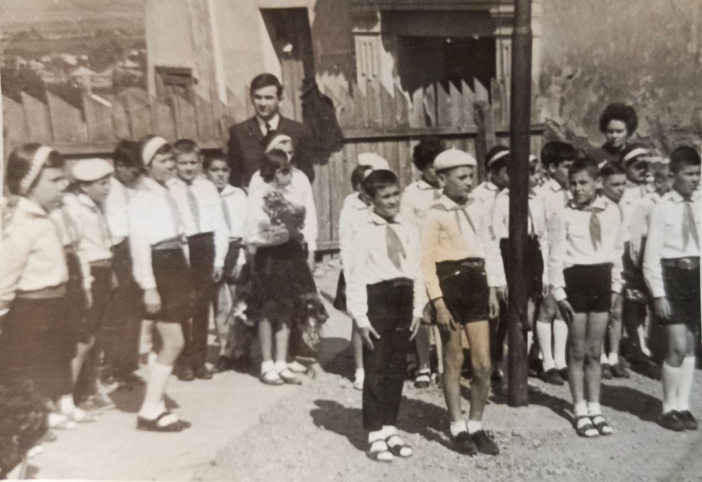 Foto di classe in bianco e nero con alunni in uniforme davanti alla scuola – ricordi di scuola elementare in Romania.