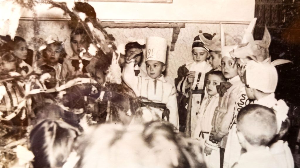 Bambini dell’asilo circondati da maestre e genitori, simbolo di un’infanzia serena e autentica tra neve, giochi e amore familiare.