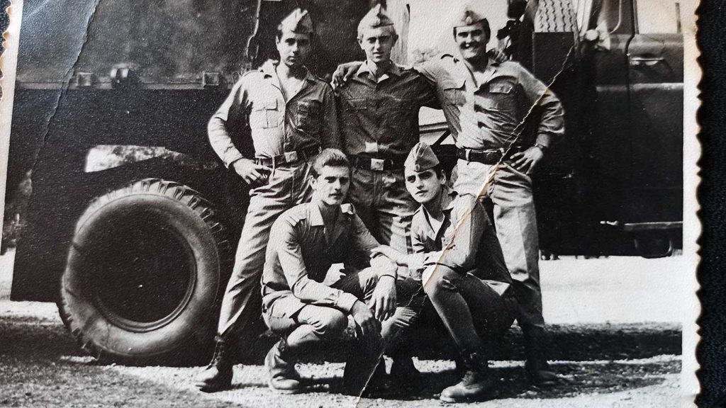 Giovani soldati rumeni durante l’addestramento militare in Romania negli anni ’70, in posa davanti a un mezzo militare dopo un’esercitazione.