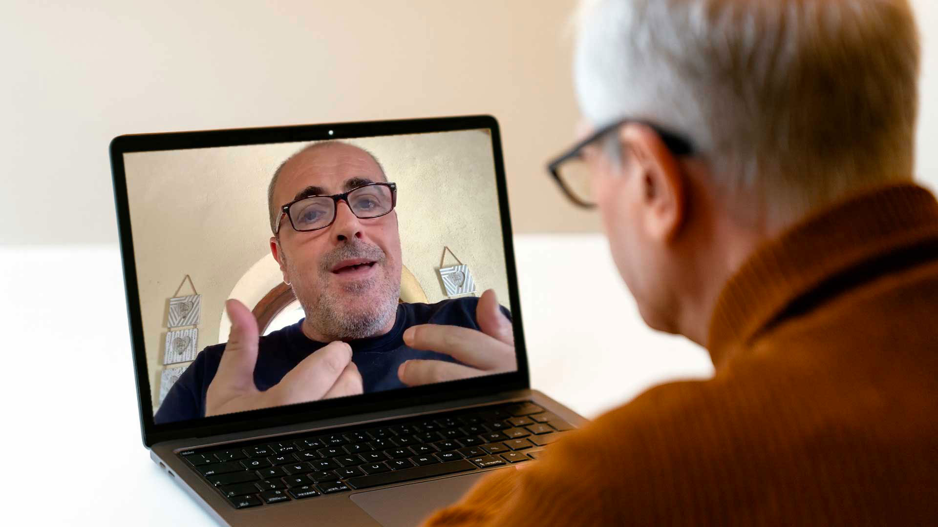 Videochiamata tra due uomini di mezza età che collaborano online. L’immagine rappresenta l’amicizia e la collaborazione online tra autore e mentore.