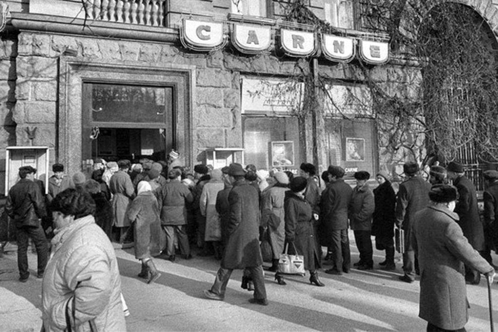 Persone in fila davanti a un negozio alimentare nella Romania comunista, in attesa di generi di prima necessità durante gli anni del regime.
