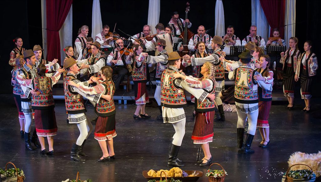 Gruppo di ballerini in costumi tradizionali durante uno spettacolo di danze folcloristiche in Romania, simbolo di libertà e identità culturale.