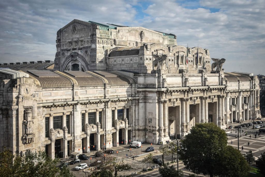 Facciata monumentale della Stazione Centrale di Milano, simbolo dei primi anni di clandestinità a Milano e delle sfide degli emigranti.