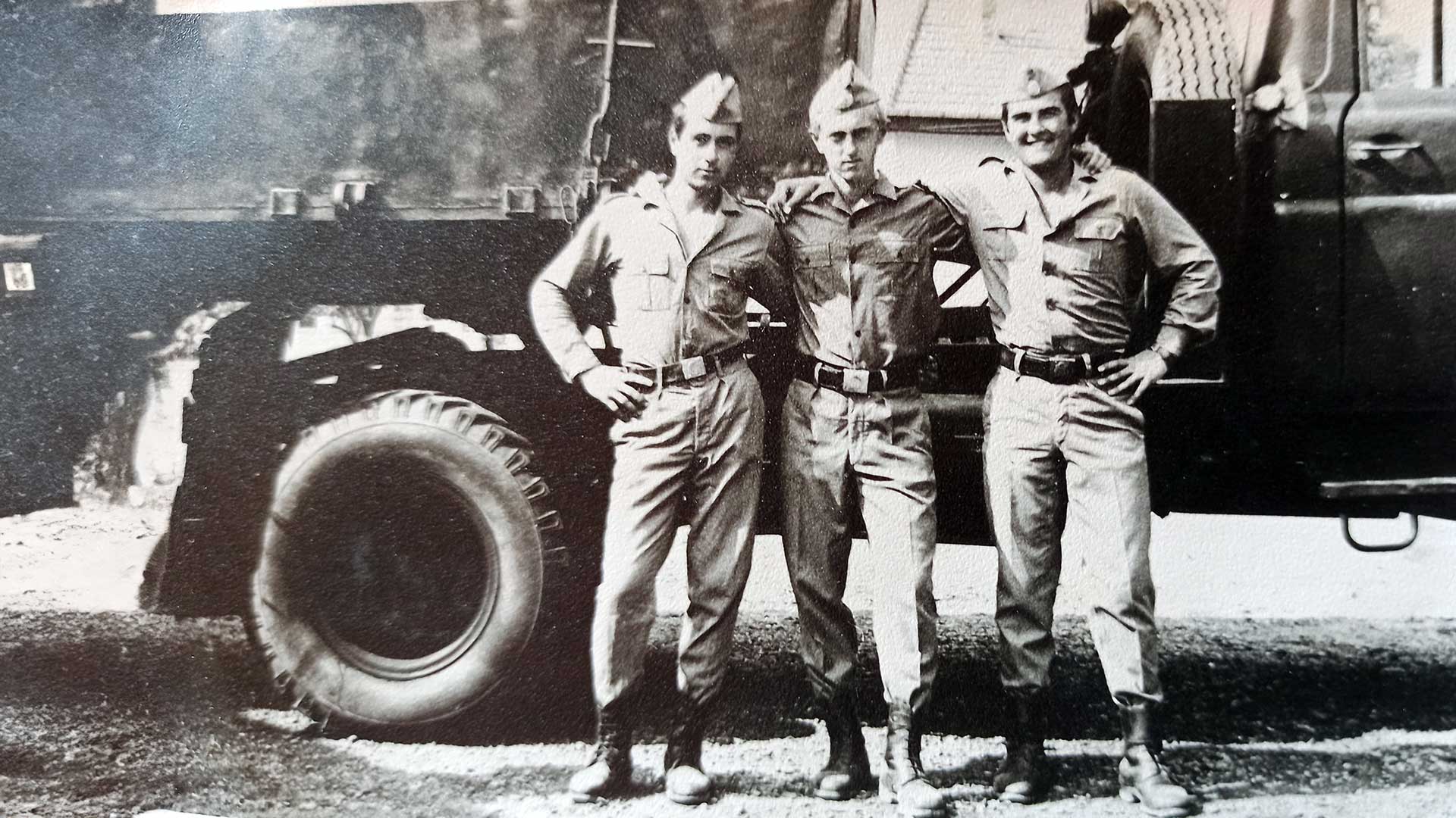 Soldati rumeni degli anni ’70 durante il servizio militare estivo, davanti ai camion dell’unità. Scena realistica che rappresenta la disciplina e la vita quotidiana nella dura scuola dell’esercito rumeno.