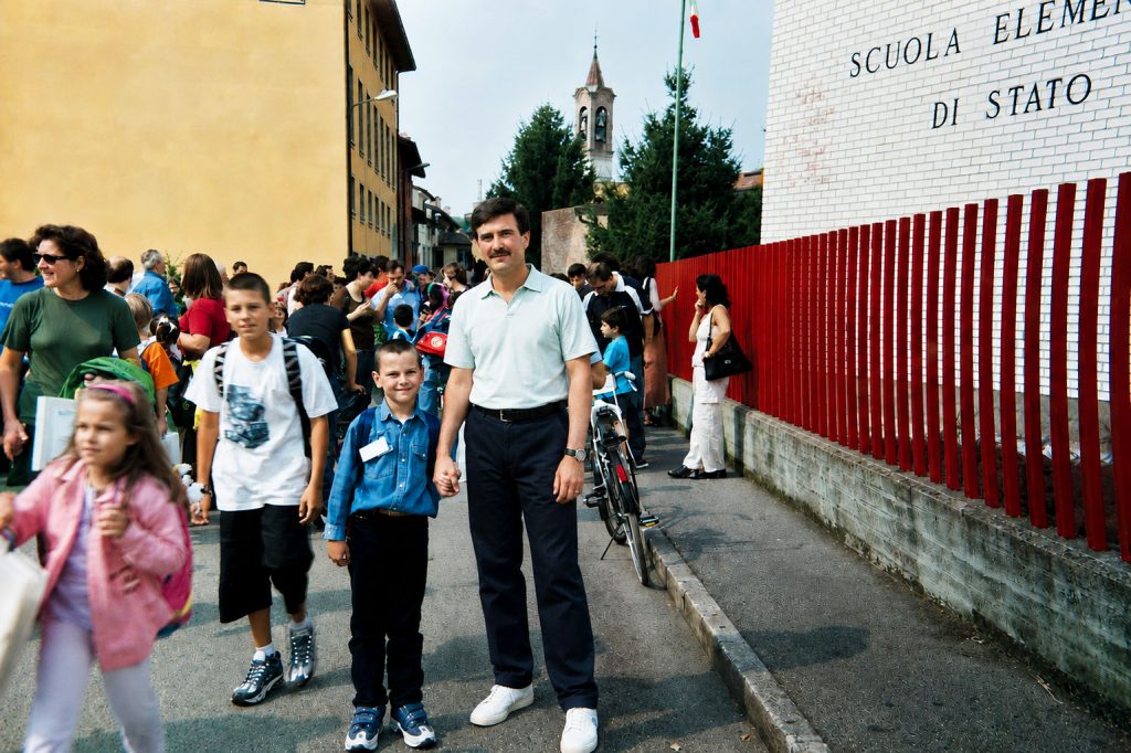 Padre e figlio davanti alla scuola elementare nel primo giorno di scuola, pronti a ricostruire una vita in Italia.